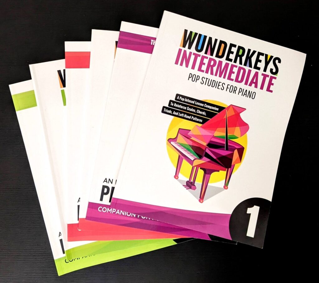 a stack of Wunderkeys intermediate pop studies for piano against a black background